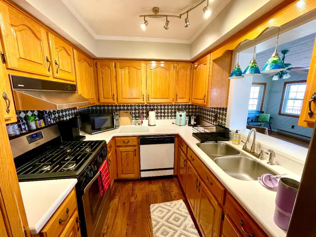 A well-lit, traditional kitchen with wooden cabinets, black and white backsplash, and modern appliances.