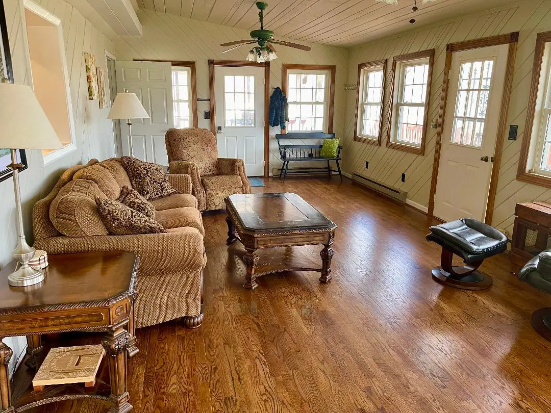 A cozy living room with wooden floors, a plush sofa, and antique-style wooden furniture.