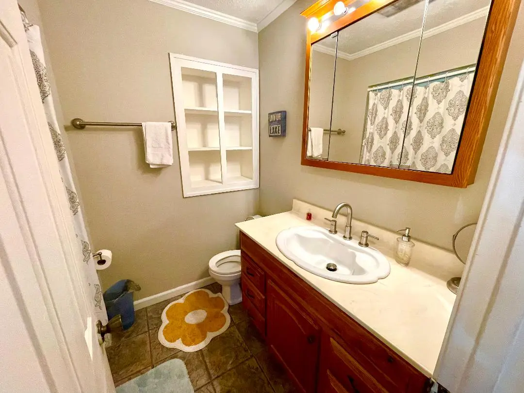 A neatly organized bathroom with a wooden vanity, white fixtures, and decorative accents.