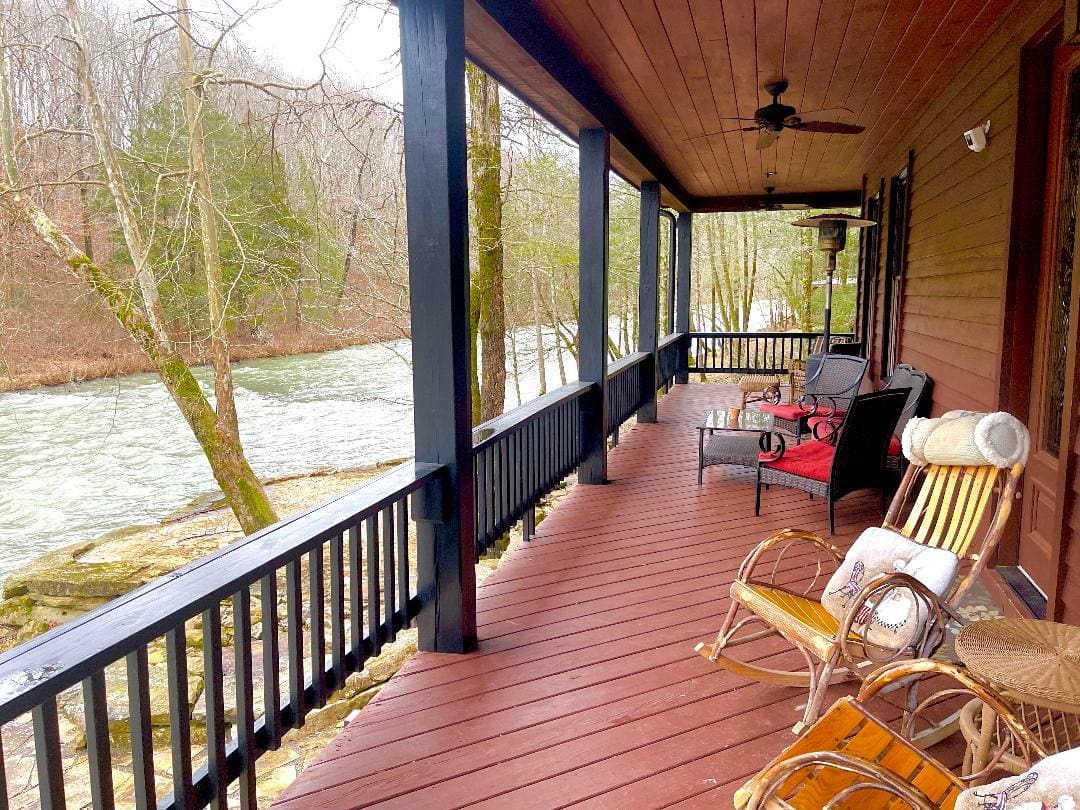 A cozy porch with outdoor furniture overlooking a tranquil river.