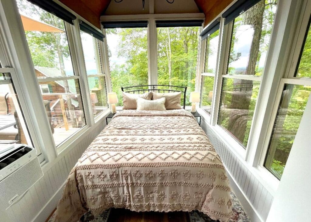 Cozy bedroom with large windows and nature view.