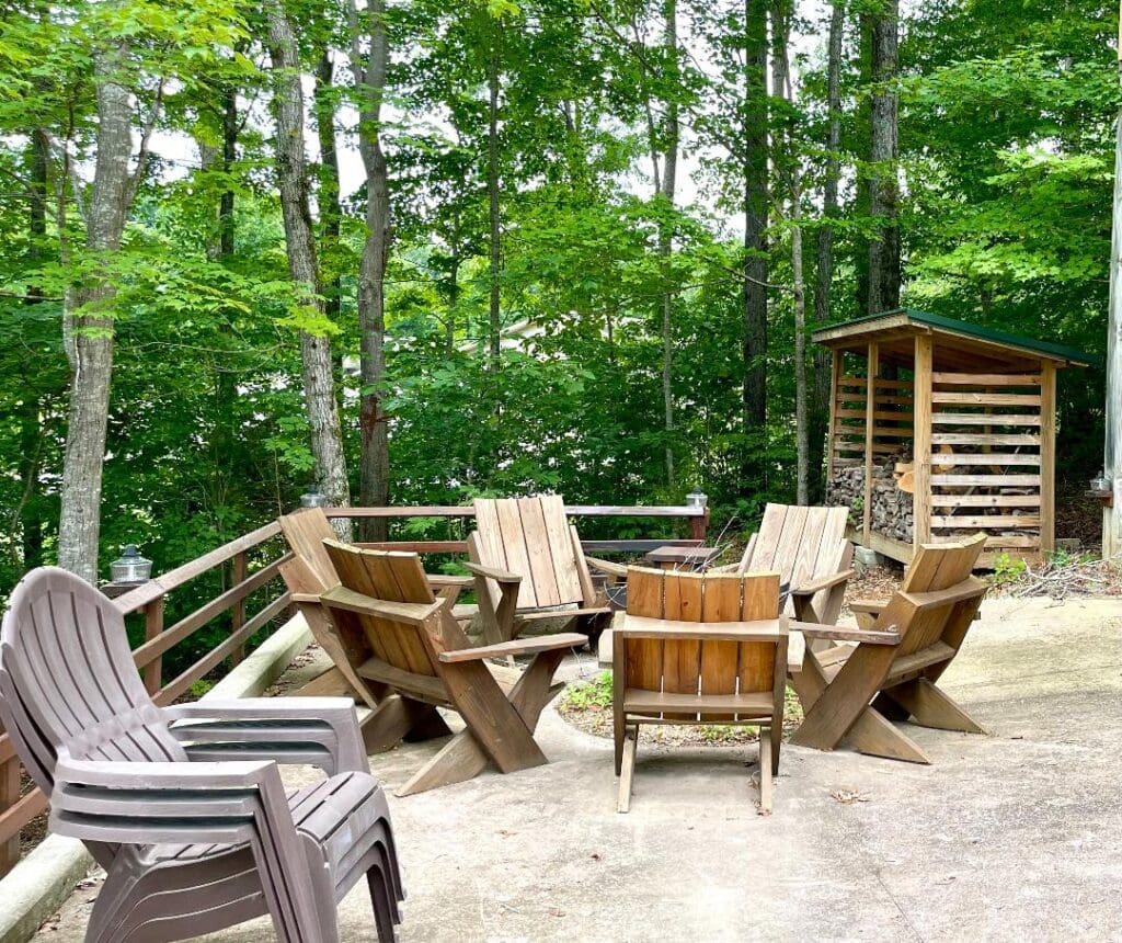 Wooden chairs on patio surrounded by trees.