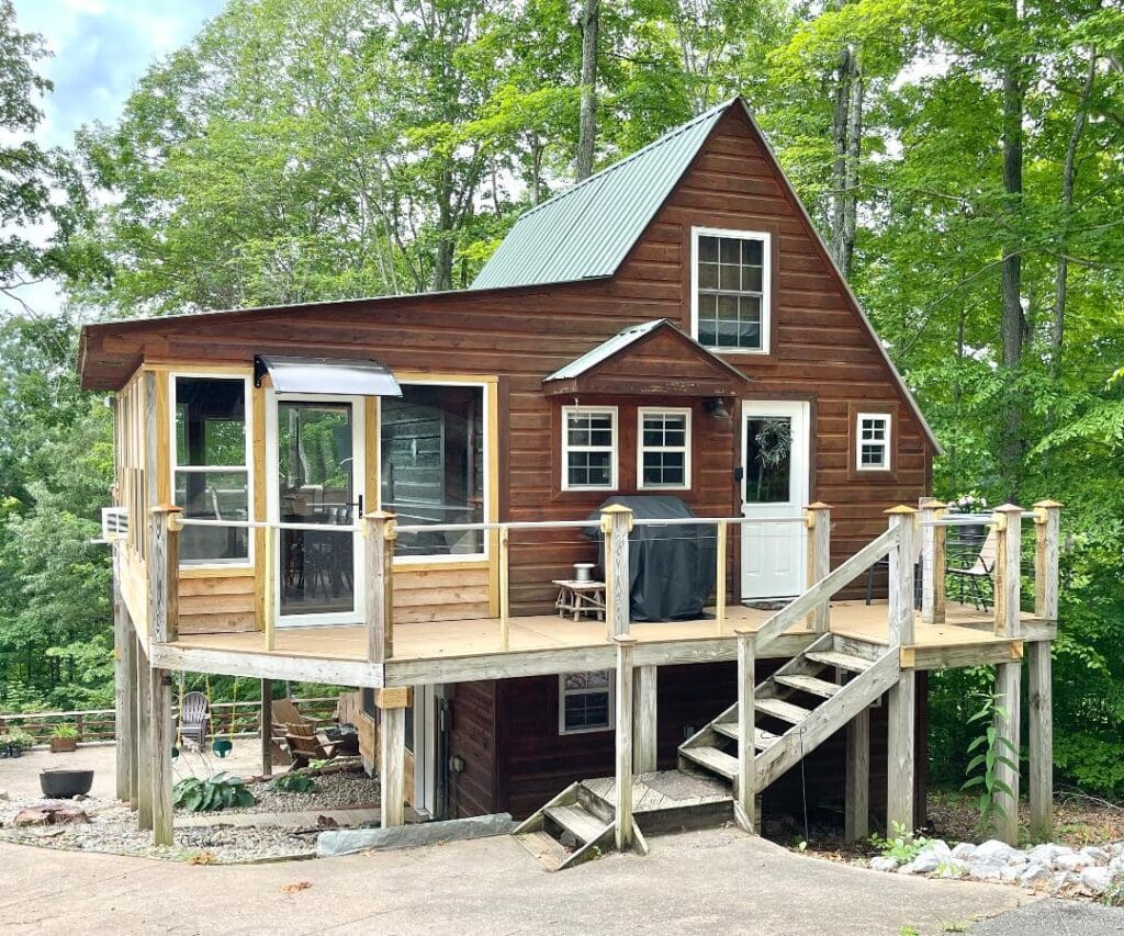 Rustic cabin with wooden deck and stairs.