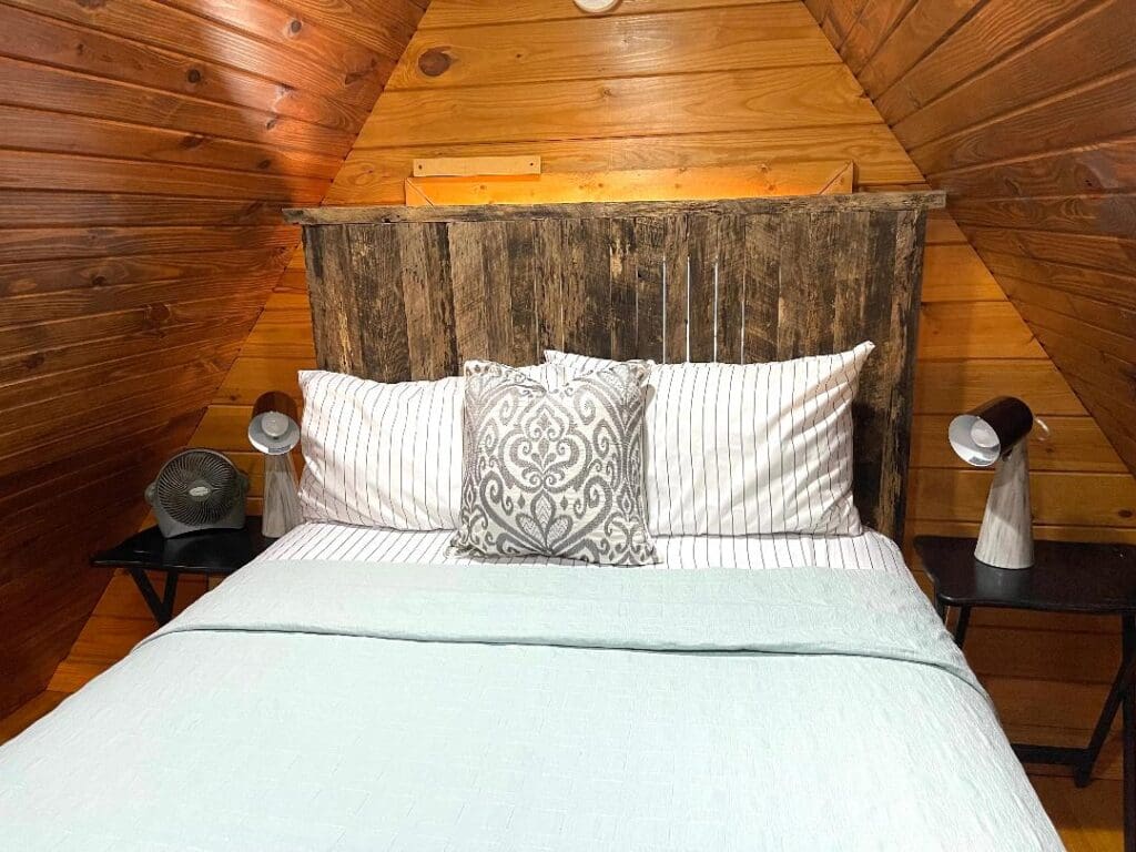 Cozy wooden attic bedroom with decorative pillows.