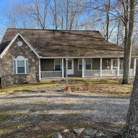 A stone home in the woods with a porch.