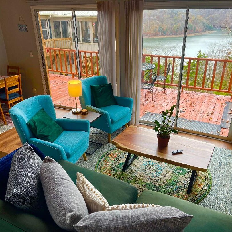 A living room with a balcony overlooking a lake.