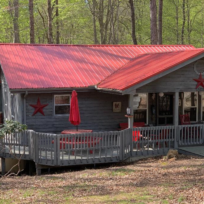 A cabin in the woods with a red roof.