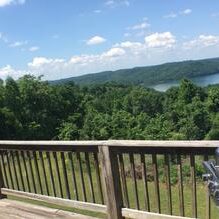 A grill on a deck overlooking a lake.